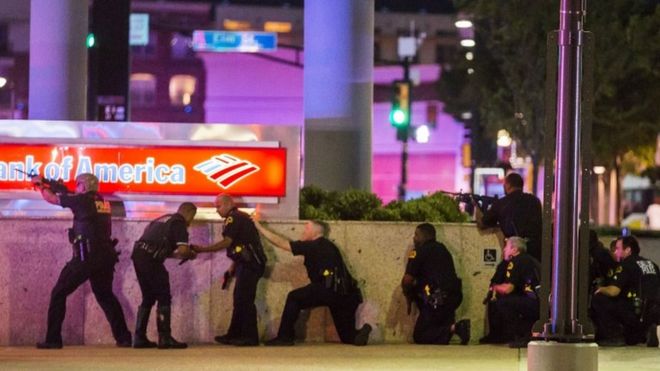 Dallas police officers take cover and return fire after shots were fired at them