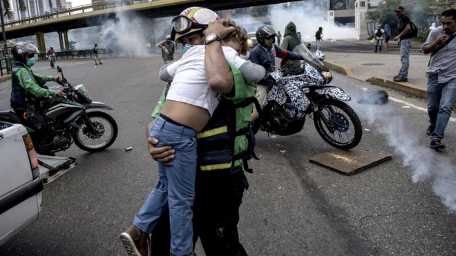 Un rescatista protege a un niño de los gases lacrimógenos.