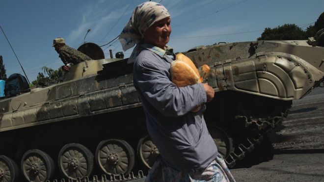 17 августа 2008 года в Гори, Грузия, грузинская женщина несет хлеб гуманитарной помощи через российский контрольно-пропускной пункт