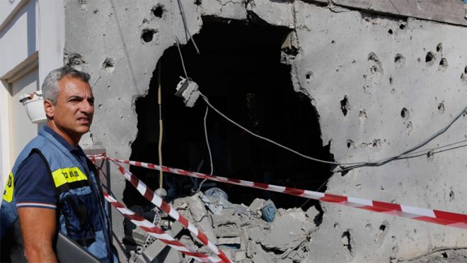 Израильтянин осматривает дом, поврежденный ракетой, в израильском городе Ашкелон (13 ноября 2018 года)