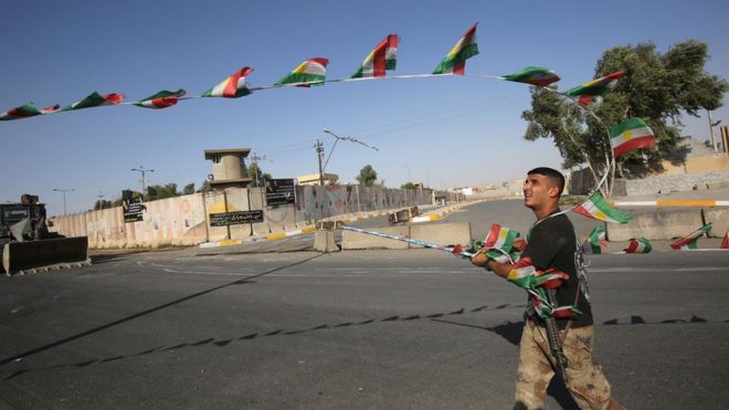 Военнослужащий иракских войск снимает курдские флаги, когда они продвигаются к центру Киркука во время операции против курдских боевиков 16 октября 2017 года