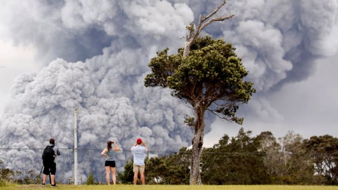 Люди наблюдают за тем, как пепел извергается из кратера Халемаумо возле вулкана во время продолжающихся извержений вулкана Килауэа на Гавайях, США, 15 мая 2018 года.