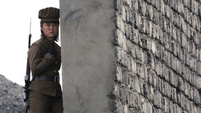 Женщина-солдат из Северной Кореи патрулирует берег реки Ялу, которая отделяет северокорейский город Синуидзу от китайского пограничного города Даньдун