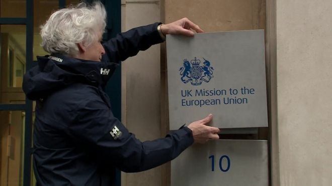 Мужчина меняет вывеску возле правительственной делегации Великобритании в ЕС, которая изменила свое название на UK Mission to the European Union