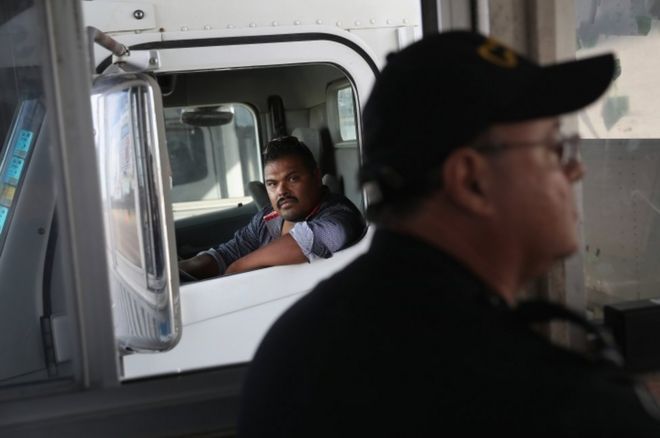 Мексиканский дальнобойщик ждет, пока 17 октября 2016 года в Ларедо, штат Техас, сотрудник таможенного и пограничного управления США обрабатывает документы на импорт.