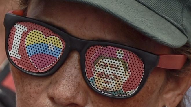 Сторонник президента Венесуэлы Николаса Мадуро в очках с изображением покойного президента Венесуэлы Уго Чавеса на митинге в Каракасе 14 мая 2016 года.