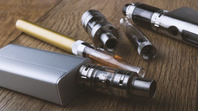 Ручка vape и различные компоненты электронной сигареты на деревянном фоне