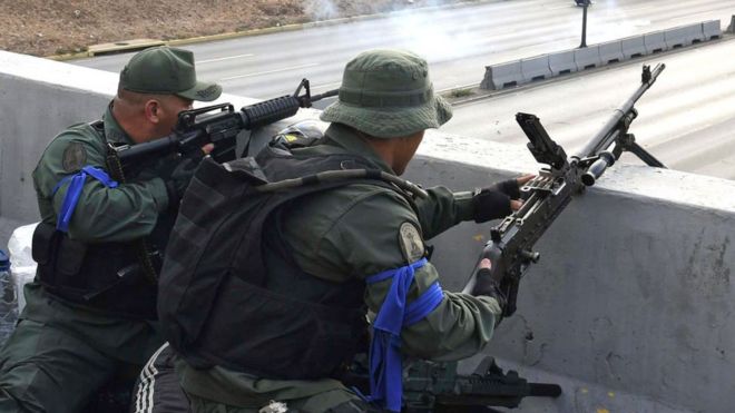 Militares con brazaletes azules apuntan sus armas