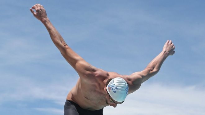 Antes de girar os braços na água, Phelps o faz no seco para pedir uma "mãozinha" da sorte