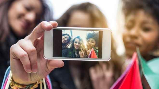 Молодые люди фотографируют с помощью мобильного телефона
