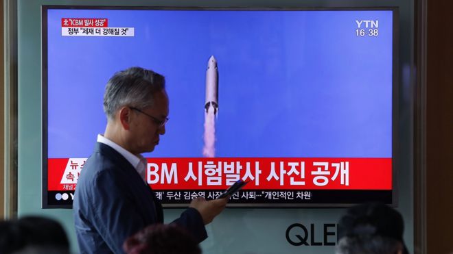 People watch a North Korea"s KRT television show a photo of North Korea"s test-launched first intercontinental ballistic missile released by Korean Central News Agency