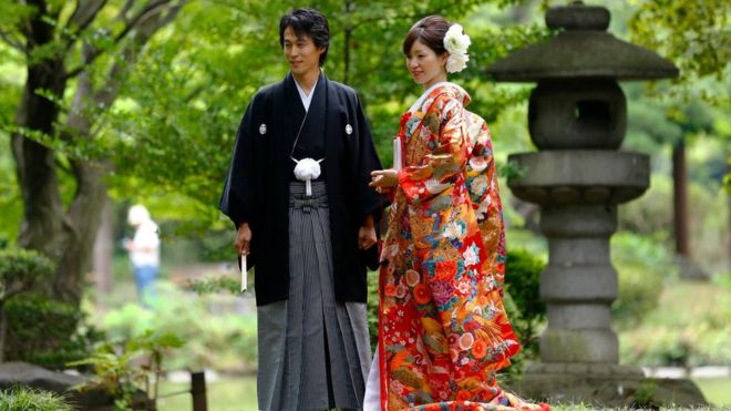 In this Aug. 12, 2015 file photo, a couple dressed in Japanese traditional wedding Kimonos pose for a wedding photograph at Hibiya park in Tokyo.