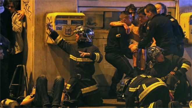 French fire brigade members aid an injured individual near the Bataclan concert hall following fatal shootings