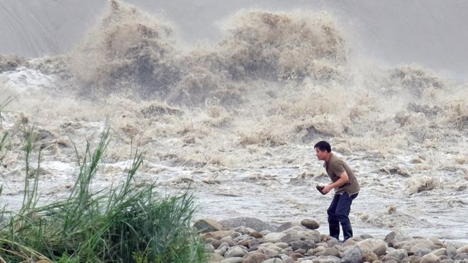 Местный житель собирает камни у реки Синдиан после того, как 29 сентября 2015 года в Новом Тайбэе прошел тайфун Дуцзюань.