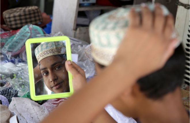 Мальчик-мусульманин-индус проверяет себя в зеркале, покупая колпаки для молитв в магазине перед фестивалем Ид аль-Фитр в Джамму, зимней столице Кашмира, Индия, 14 июня 2018 года
