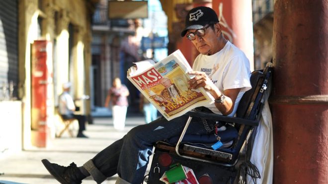 Обувщик читает газету в центральном Сан-Сальвадоре 14 марта 2013 года, на первой полосе которого весть о выборах Папы Франциска.