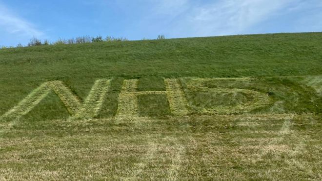 Логотип NHS, вырезанный в траве в аэропорту Бирмингема