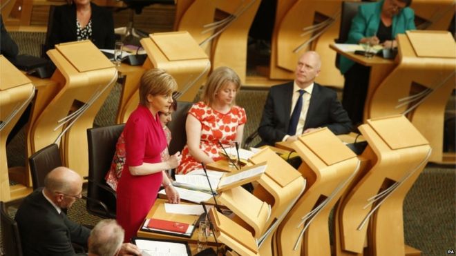 Первый министр Никола Осетрин (слева) выступает с речью, в которой излагает свою законодательную программу на предстоящий год, в шотландском парламенте в Эдинбурге