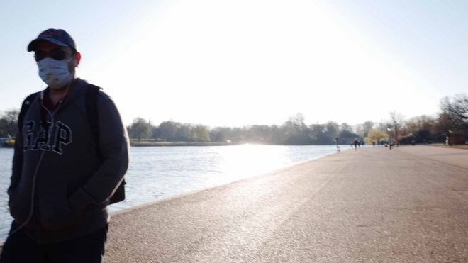 Man walks alone by Regents Park pond, London