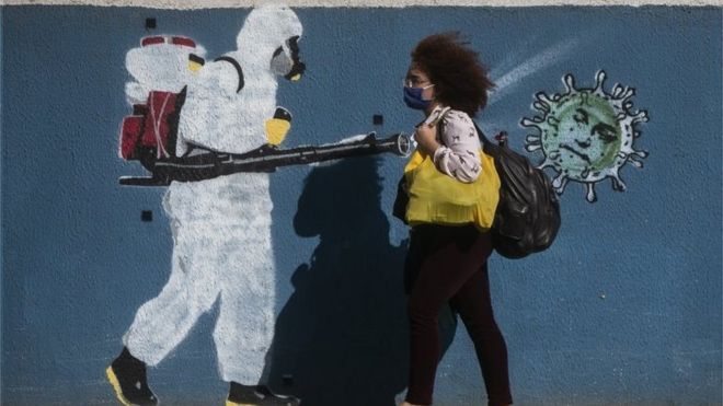 Mulher caminha diante de grafiti no Rio
