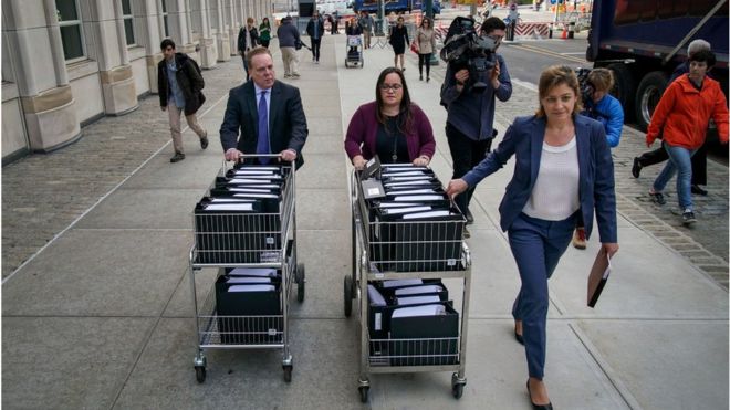 По прибытии в США сотрудники и члены прокуратуры толкают тележки, полные судебных документов по делу США против Кейта Раньера.Окружной суд Восточного округа Нью-Йорка