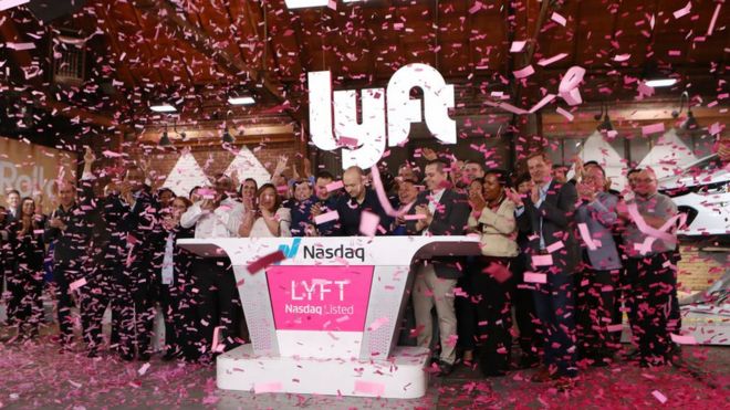 El CEO de Lyft en el centro tocando la campana de apertura de Nasdaq para celebrar la salida a la bolsa de la empresa.