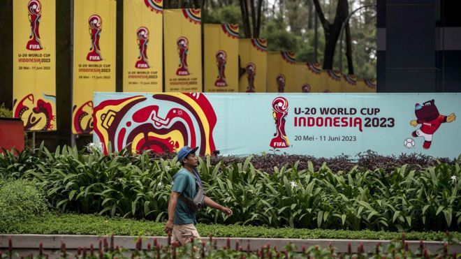 Warga berjalan di dekat papan promosi Piala Dunia U-20 Indonesia 2023 di kawasan GBK Arena, Jakarta, Kamis (30/3/2023).