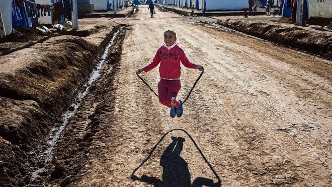 Перемещенная иракская девушка, которая бежала от непрекращающегося столкновения между джихадистами группы Исламского государства (ИГИЛ) и правительственными силами вокруг Мосула, прыгает через скакалку в лагере беженцев Хазер рядом с курдским контрольно-пропускным пунктом Аски-Калак, в 40 км к западу от Арбиля, столицы автономного округа. Курдский район северного Ирака, 6 января 2017 года.