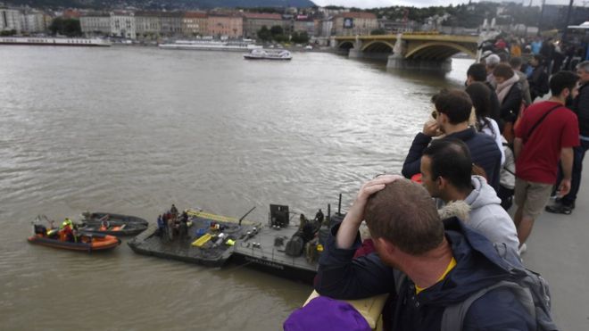 Люди на Мосте Маргарет наблюдают за операциями по подготовке восстановления опрокинутой лодки в Будапеште