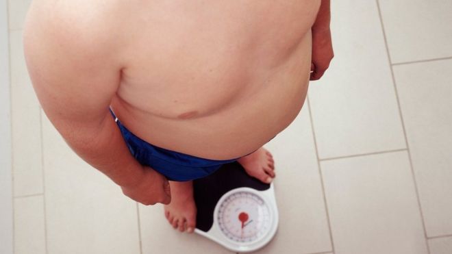 Ребенок с избыточным весом стоит на весах