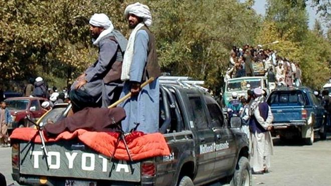 Ополченцы талибов стоят в пикапе, когда демонстранты едут впереди на машине в Кабуле, Афганистан, среда, 26 сентября 2001 года.