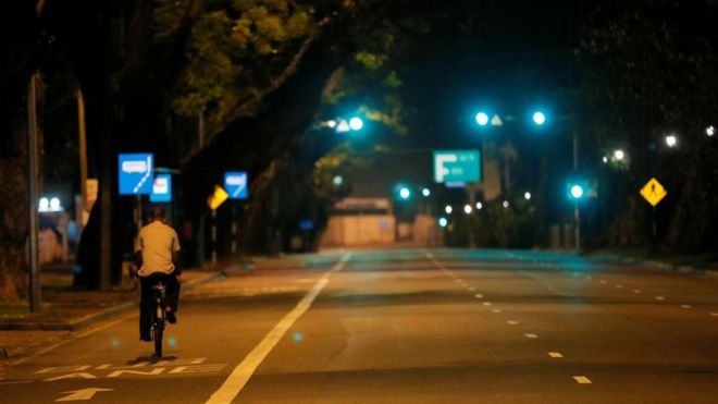 A man rides his bicycle along a road during the curfew after multiple explosions