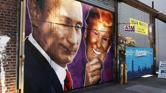 Фреска с изображением подмигивающего Владимира Путина, снимающего маску Дональда Трампа, нарисована на витрине магазина в Бруклине, Нью-Йорк