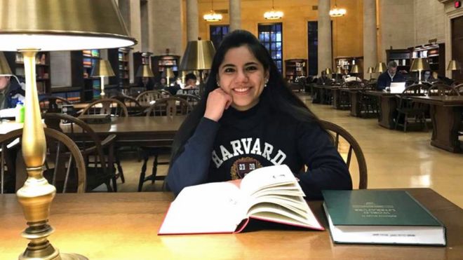 Dafne Almazán sentada em uma biblioteca com um moletom onde lê-se Harvard. Jovem de 17 anos foi aceita no curso de matemática da instituição