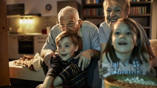 Сток фото - Бабушка и дедушка смотрят фильм вместе со своими внуками крупным планом