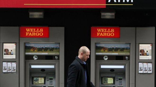 Мужчина идет мимо банкоматов Wells Fargo