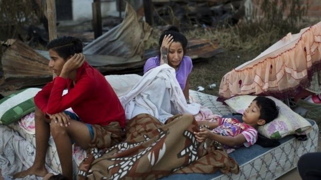 A Ecuadorian family sleeps outside following a powerful earthquake