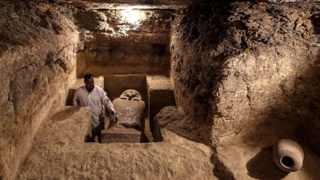 أثري مصري يفحص غرفة دفن تم العثور عليها في الكشف الأثري