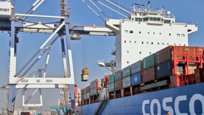 Контейнер выгружается с грузового судна China Ocean Shipping Company (COSCO) в порту в Яньтае, провинция Шаньдун, Китай