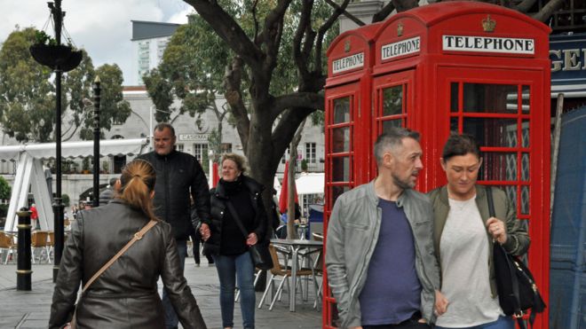 Люди в Гибралтаре проходят мимо красной телефонной будки