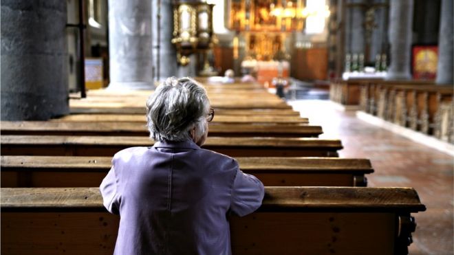Solitary woman kneeling in church