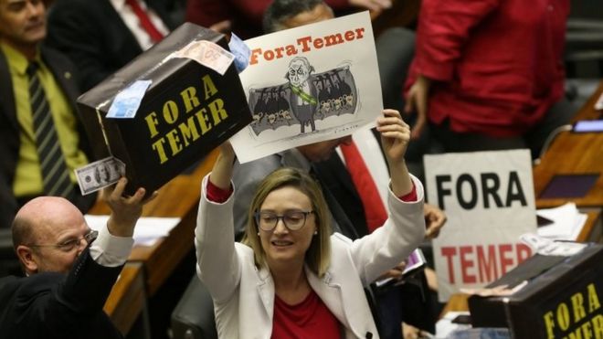 Opposition deputies of the lower chamber of Brazil's Congress hold a suitcase with fake money before a vote on sending corruption charges against President Michel Temer to the Supreme Court for trial in Brasilia, 2 August 2017