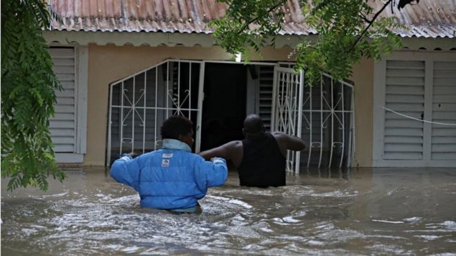 Люди входят в дом во время наводнения, вызванного прохождением Штормовой Лауры в Азуа, Доминиканская Республика, 23 августа 2020 года.