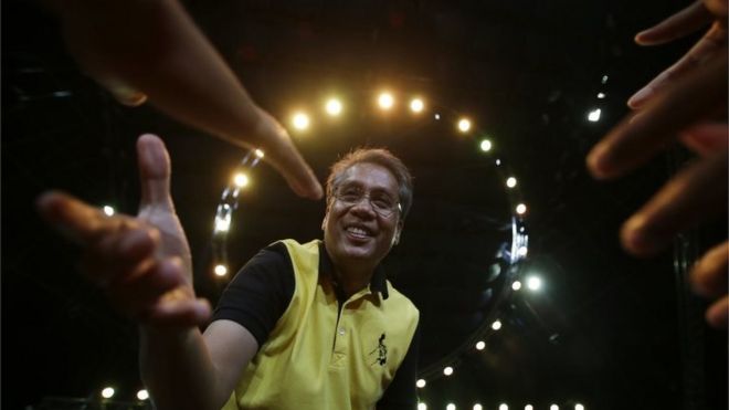 Мар Роксас, бывший министр внутренних дел и местного самоуправления, а теперь кандидат в президенты, протягивает руку помощи сторонникам во время предвыборной кампании в пригороде Кесон, к северу от Манилы