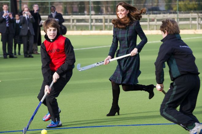 Екатерина, герцогиня Кембриджская, играет в хоккей на траве в пальто и на каблуках в школе Святого Андрея 30 ноября 2012 года