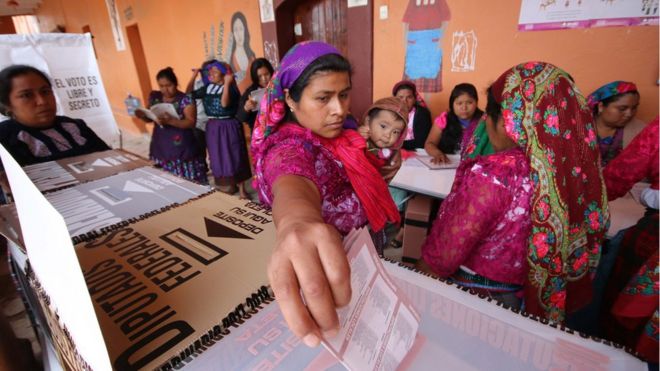 A woman holding a baby casts her ballot at a polling station during the presidential election in San Bartolome Quialana, in Oaxaca state, Mexico, July 1, 2018.