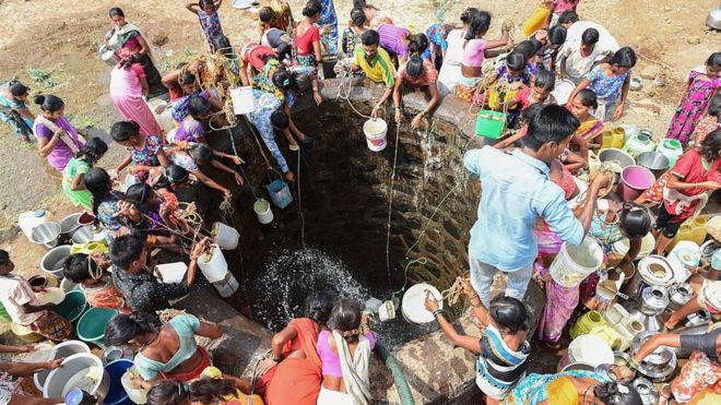 Personas sacando agua de un pozo.