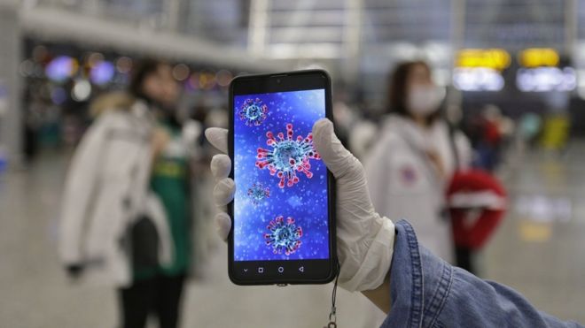 A passenger shows an illustration of the coronavirus on his mobile phone at Guangzhou airport in Guangzhou, Guangdong Province, China, 23 January 2020