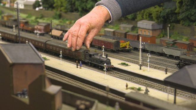 Мужчина держит модель железной дороги