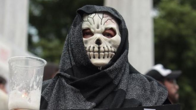 Женщина в маске черепа принимает участие в акции протеста с требованием справедливости по делу о многократном убийстве, в котором Рубен Эспиноса 8 августа 2015 года